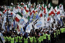 Security members walk in front of demonstrators during a pre-electoral rally of Italian Prime Minister Silvio Berlusconi's ruling center-right party "Popolo della Liberta" (PDL) on March 20, 2010 in Rome. The media tycoon has said the elections in 13 of Italy's 20 regions on March 28 and 29 will be a key barometer of his centre-right coalition's performance since he returned to power for a third time in 2008. The Berlusconi camp is on the defensive after being hit by a series of embarrassments as top officials were caught up in corruption scandals.  AFP PHOTO / Filippo MONTEFORTE